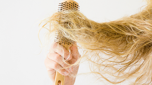 Image made in Canva. Picture of a woman trying to get a hairbrush through frizzy hair.